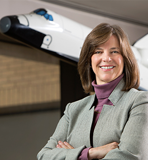 Bonnie Dunbar stands with a model of the space shuttle